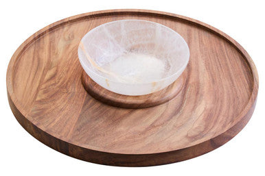 A clear quartz bowl on an acacia wood circular tray with visible grain for an onyx chip and dip platter