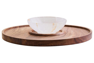 A white marble onyx chip and dip platter with golden veining on a round dark acacia wood serving tray