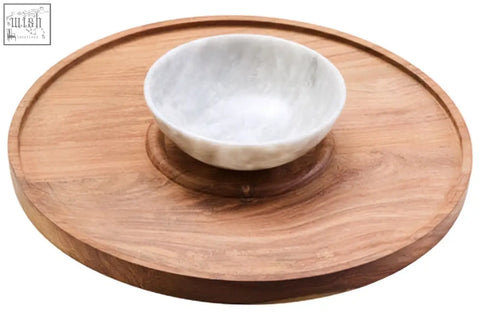 A white marble chip and dip bowl with subtle veins sits on a round kora acacia wood serving board