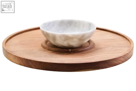 A white marble chip bowl with gray veining on a kora acacia wood circular serving tray for chip and dip use
