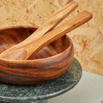 A rich warm-toned kora olive wood flat salad servers set with matching utensils inside a wooden salad bowl