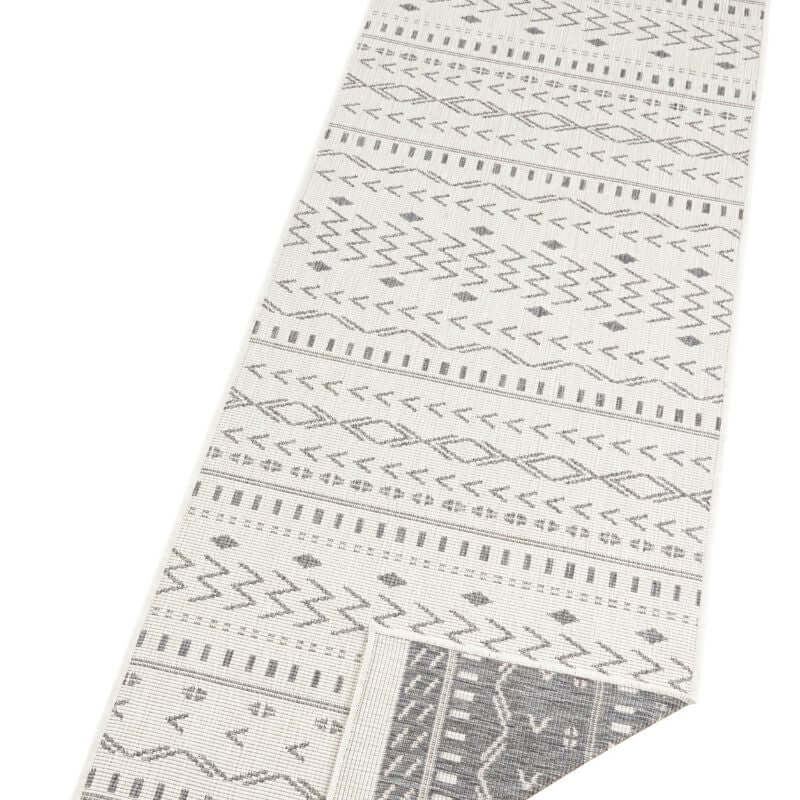A kuba reversible indoor-outdoor rug with off-white background and dark gray geometric zigzag and diamond patterns