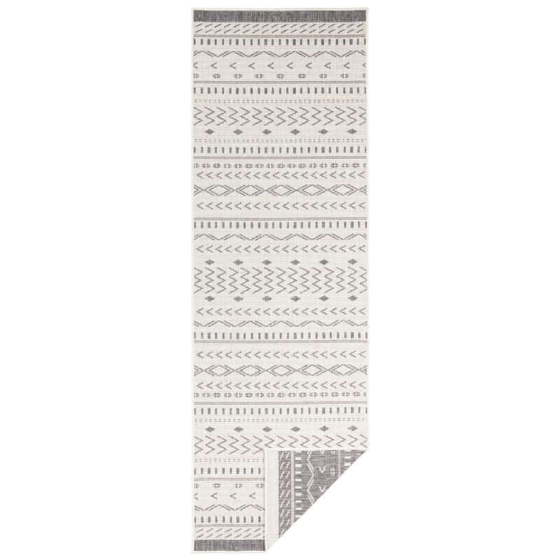 A kuba reversible indoor outdoor rug with a long white base and intricate gray geometric patterns