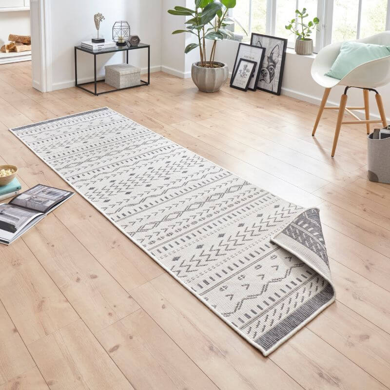 A kuba reversible indoor-outdoor runner rug with a white base and intricate gray geometric patterns