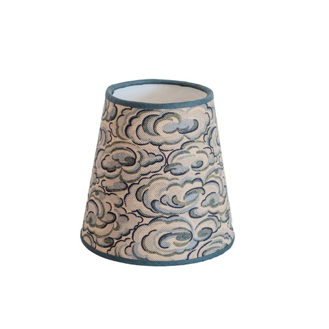 A kumo clouds lampshade with beige fabric, gray and blue cloud patterns, and teal trim in a conical shape