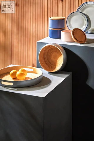 Gray ceramic small silver tray with wooden rim and side handles holding three yellow lemons in kyoto style