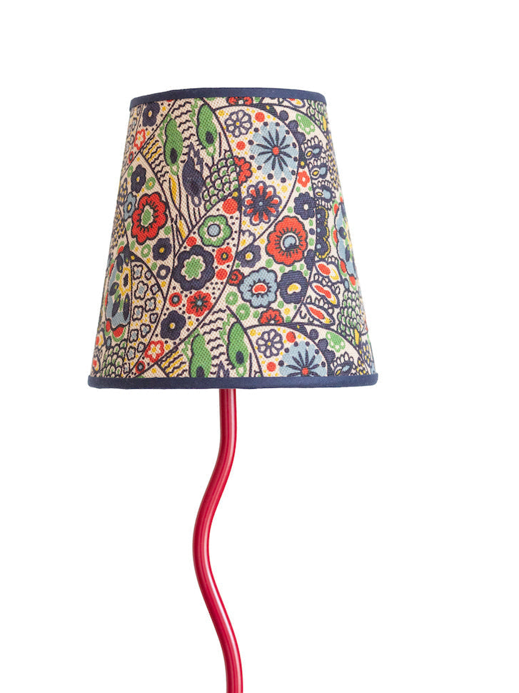 A vibrant red metal lamp with a kyoto woodblock floral and peacock feather patterned lampshade on off-white background