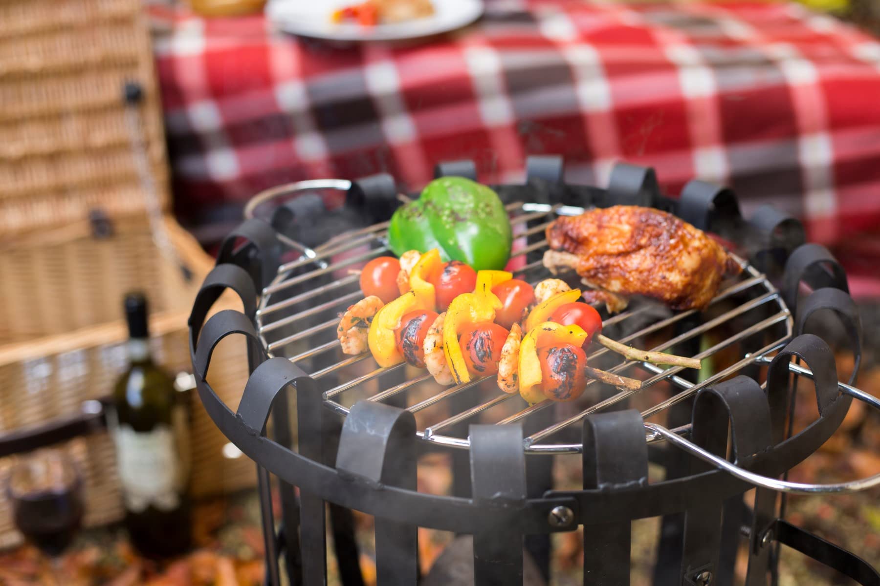Black metal circular grill firebasket with food skewers and green pepper perfect for outdoor gatherings by hacienda vancouver