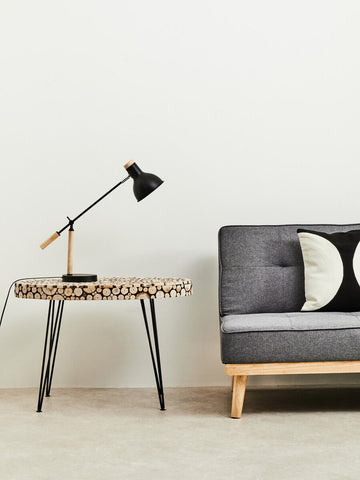 Black and wood-handled desk lamp on lacuna fir wood oval coffee table made of stacked fir wood tree rings