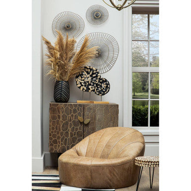 Tan leather shell chair with quilted texture and cushioned form next to lacuna fir wood round side table