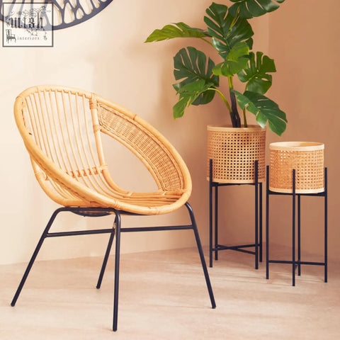 A lagom natural rattan chair with a curved seat and backrest supported by black iron legs