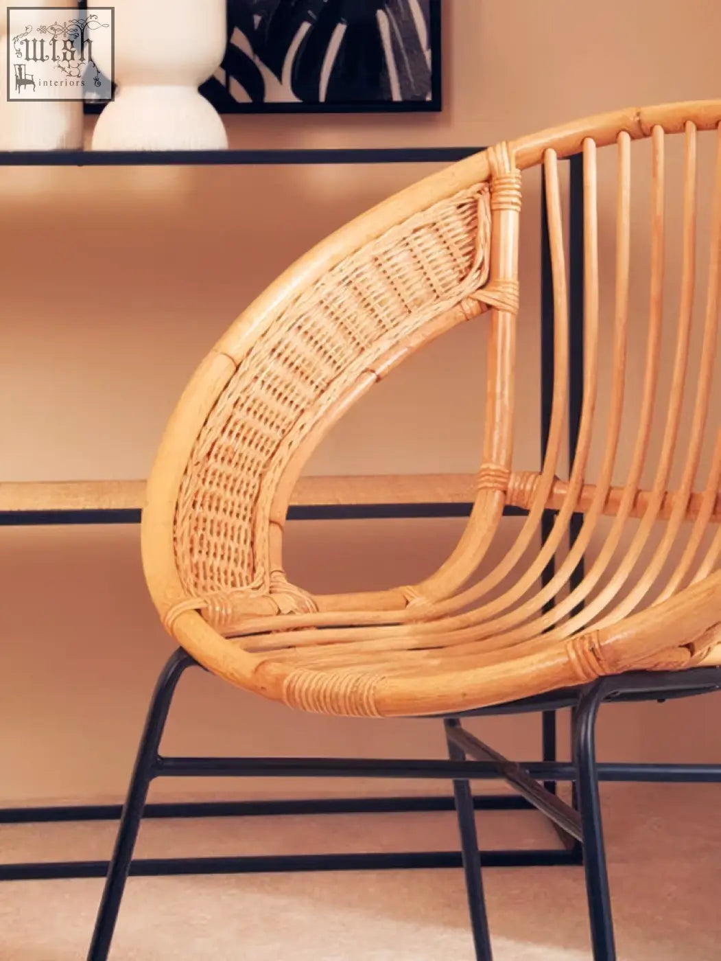 A lagom natural rattan curved back chair with light brown woven seat and black iron chair legs