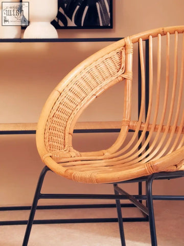 A lagom natural rattan curved back chair with light brown woven seat and black iron chair legs