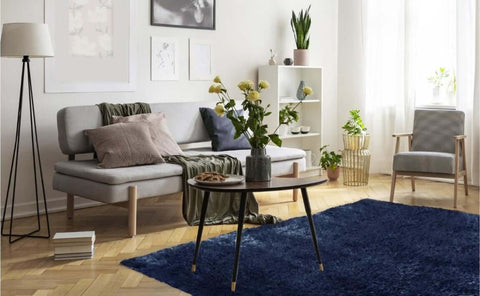 A sleek dark gray ceramic vase with matte finish holding tall yellow flowers on a lagom navy shaggy rug