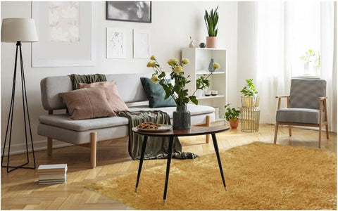 A sleek dark gray ceramic vase with pale yellow flowers sits on a lagom ochre shaggy rug adding cozy style