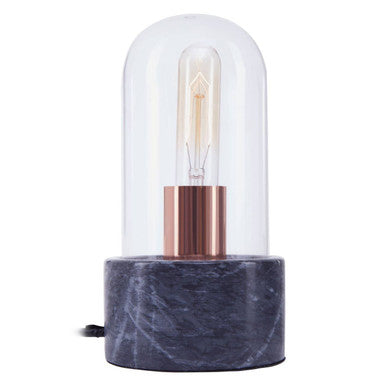 A sleek lamonte bell lamp with a clear glass dome, copper base, and black marble base pedestal