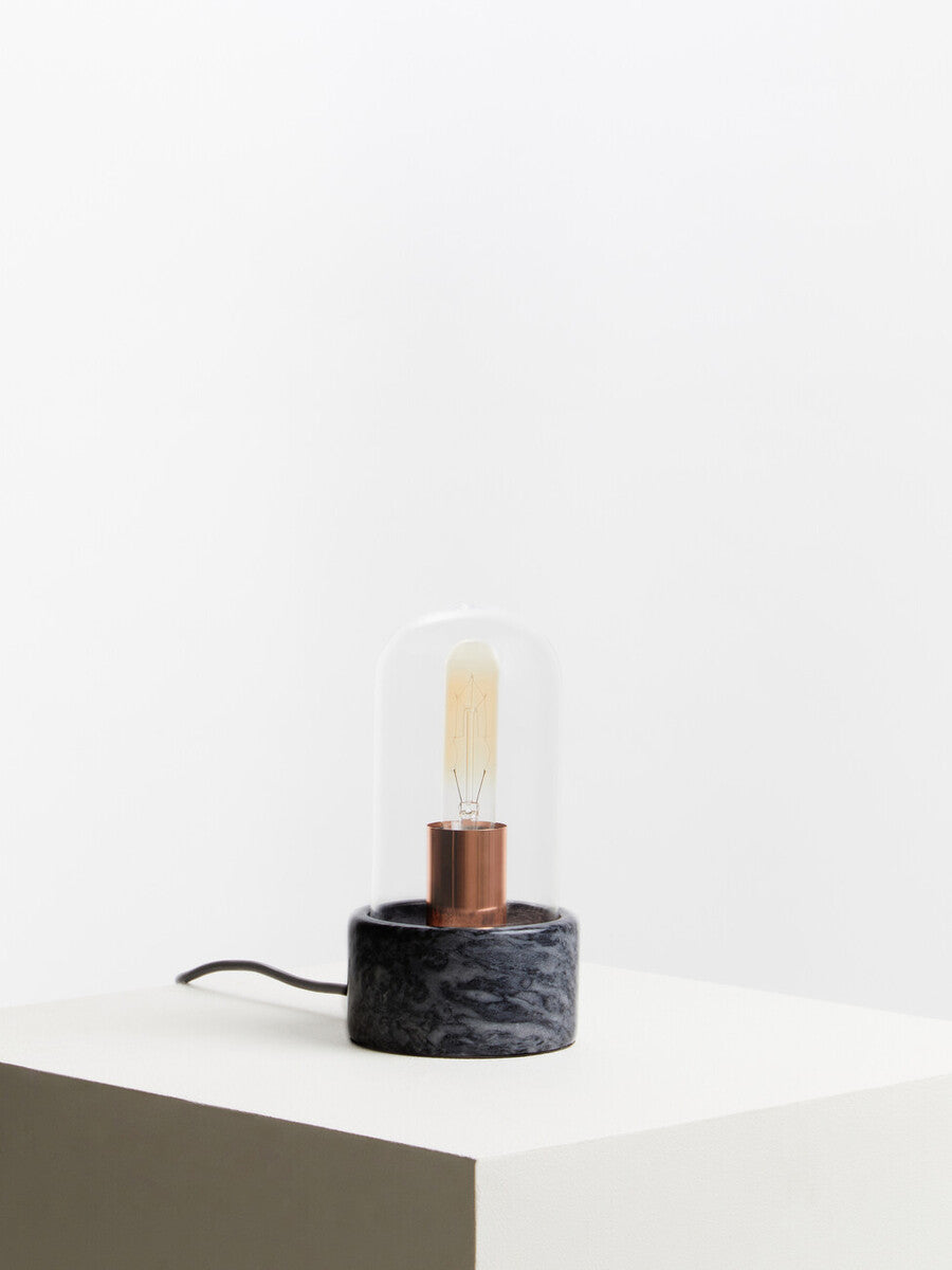 Lamonte bell lamp with black marble base features a clear glass dome and exposed copper filament bulb