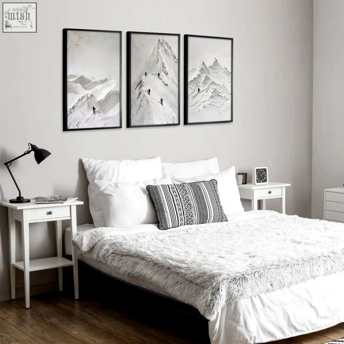 Three black-framed monochrome mountain landscape art prints in white and grey hang as wall art above a bed