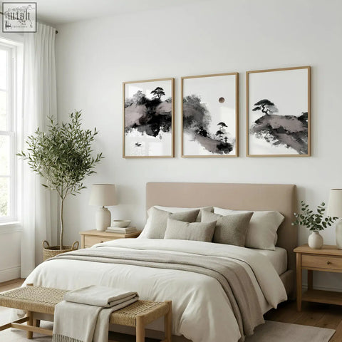 Set of three japanese ink wash landscape prints in black white with maroon moon and pine trees in light wood frames above bed