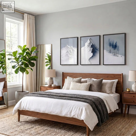Wooden bed with warm brown finish and white bedding with dark gray throw in a room featuring landscape wall art of nordic snow mountains