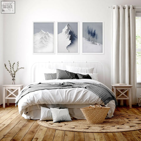 White metal bed frame with curved headboard and matching nightstands below nordic snow mountains landscape wall art set