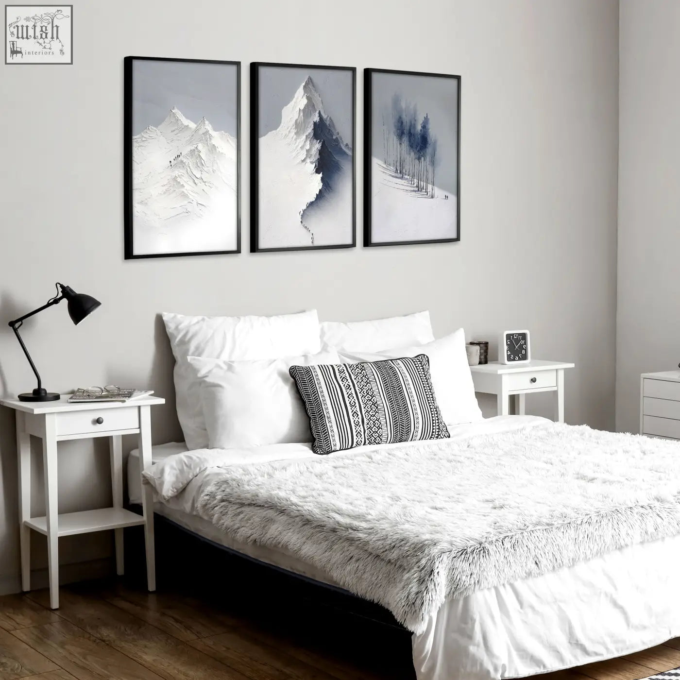 Three framed black and white nordic snow mountains and winter forest landscape wall art prints hanging above the bed