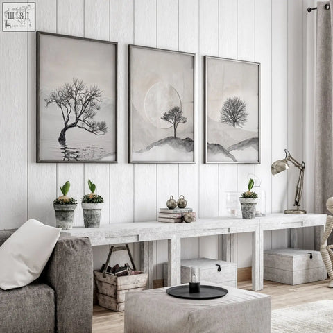 Three framed black and white minimalist trees and moon landscape piece wall art hanging on white wooden wall for living room