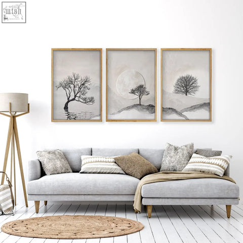 Three piece black and white tree wall art with light wood frames above a gray sectional sofa for living room decor