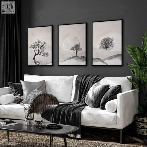 Three framed black and white minimalist tree wall art pieces hang above a white sofa in living room decor