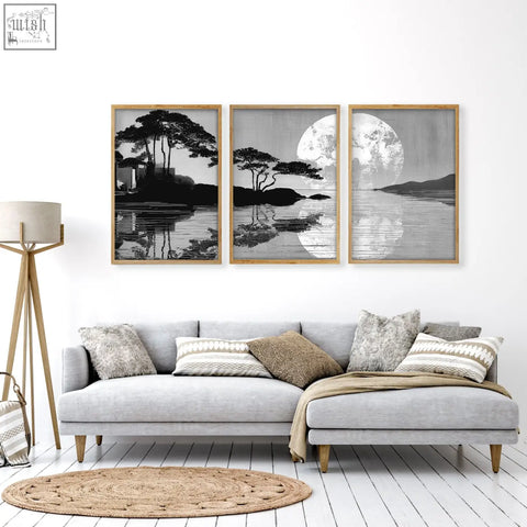 Three framed black and white japanese moonrise silhouette prints with wooden frames hang above a gray sectional sofa in a large art living room setup
