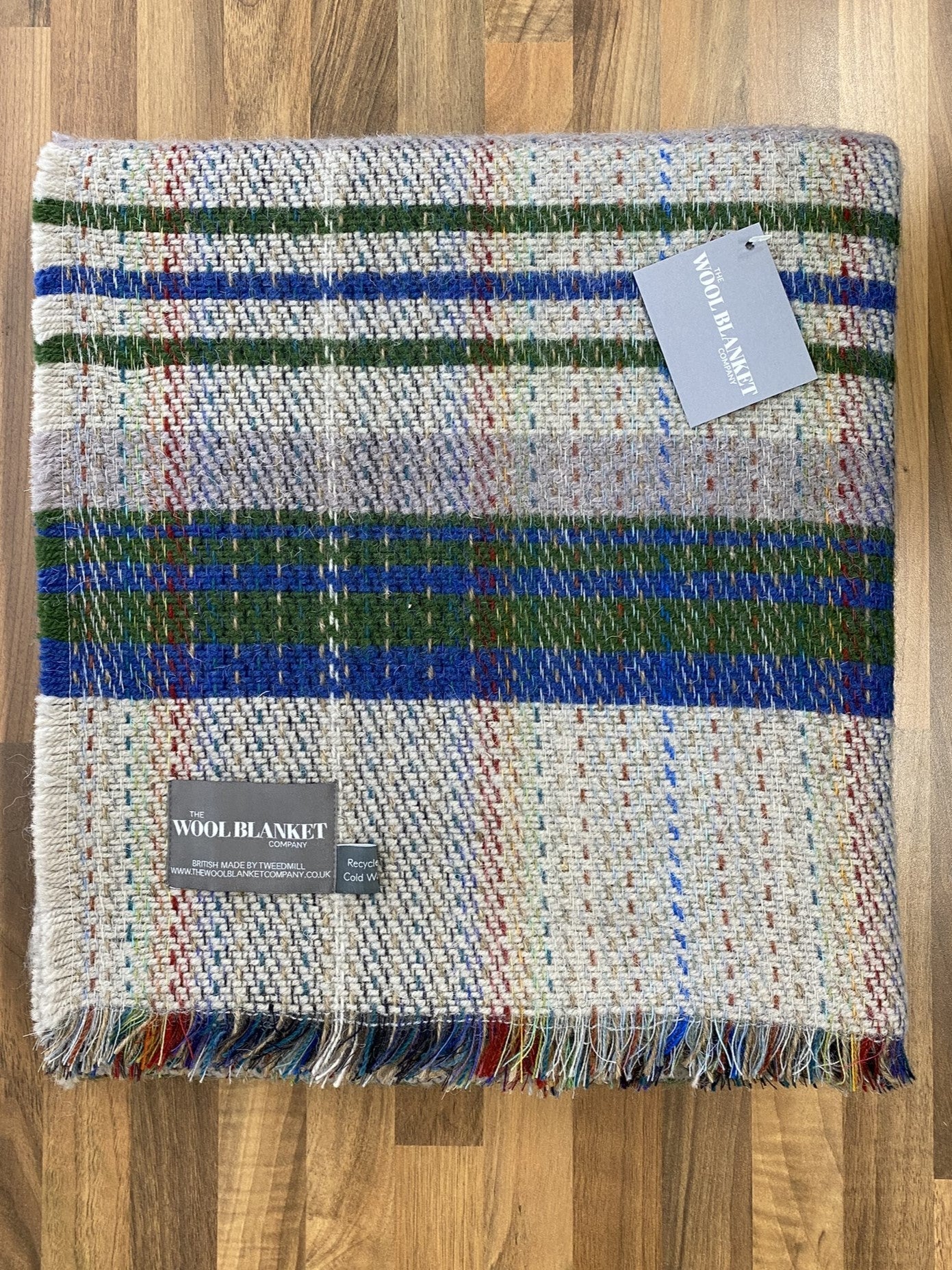 A cozy large checked random recycled wool blanket in multicolored plaid with fringed edges and textured weave