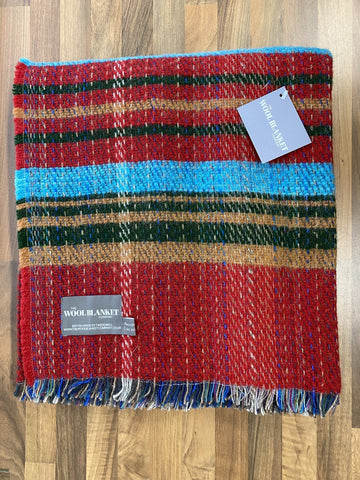 A large checked random recycled wool blanket with bold multicolored stripes and fringed edges in vibrant hues