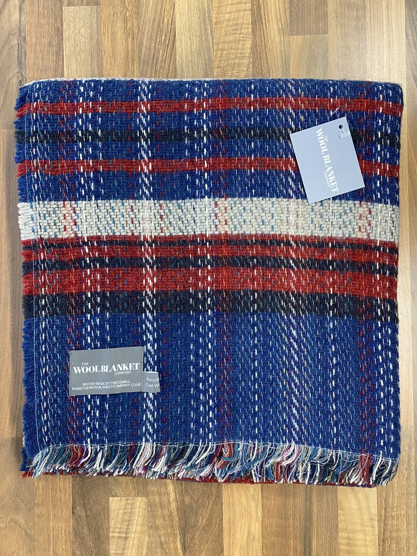 A cozy large checked random recycled wool blanket in blue red and white plaid with fringed edges from the wool blanket company