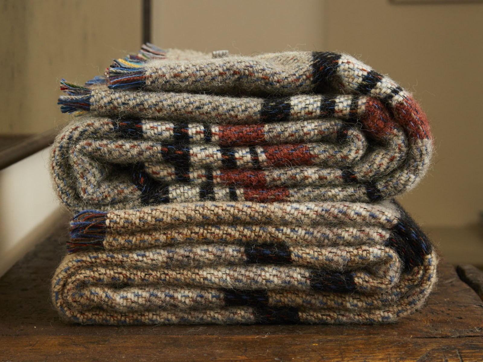 A cozy large checked random recycled wool blanket in earthy beige black and rust tones with a rustic plaid pattern