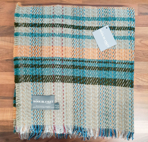 A cozy large checked random recycled wool blanket with a teal olive beige peach plaid pattern and fringed edges