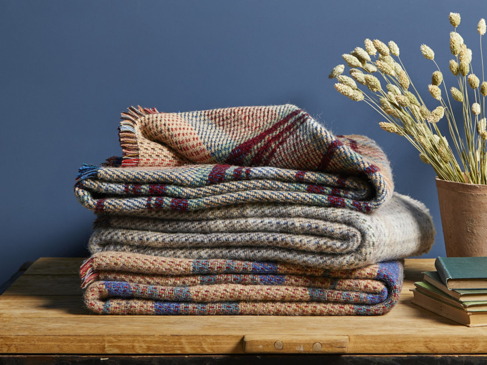 Stack of cozy large checked random recycled wool blankets in earthy tones with textured plaid patterns