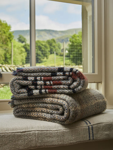 Stacked large checked random recycled wool blanket with tweedy plaid pattern in earthy grey black red and beige tones
