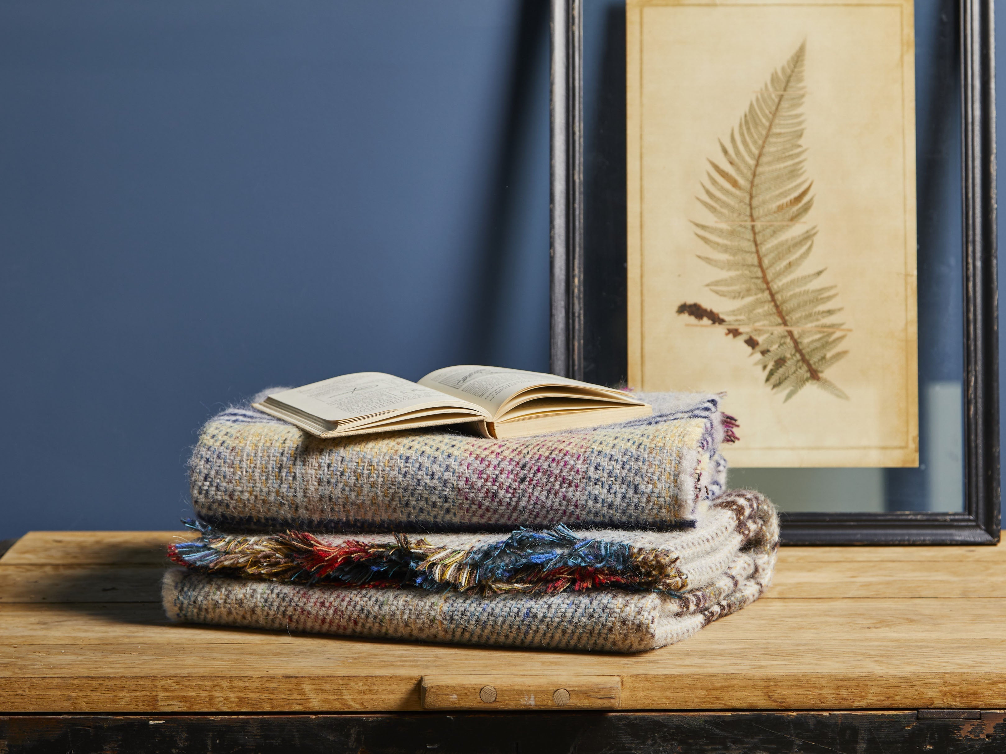 Stacked large checked random recycled wool blankets with multicolored pattern and fringed edges for cozy use