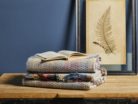 Stacked large checked random recycled wool blankets with multicolored pattern and fringed edges for cozy use
