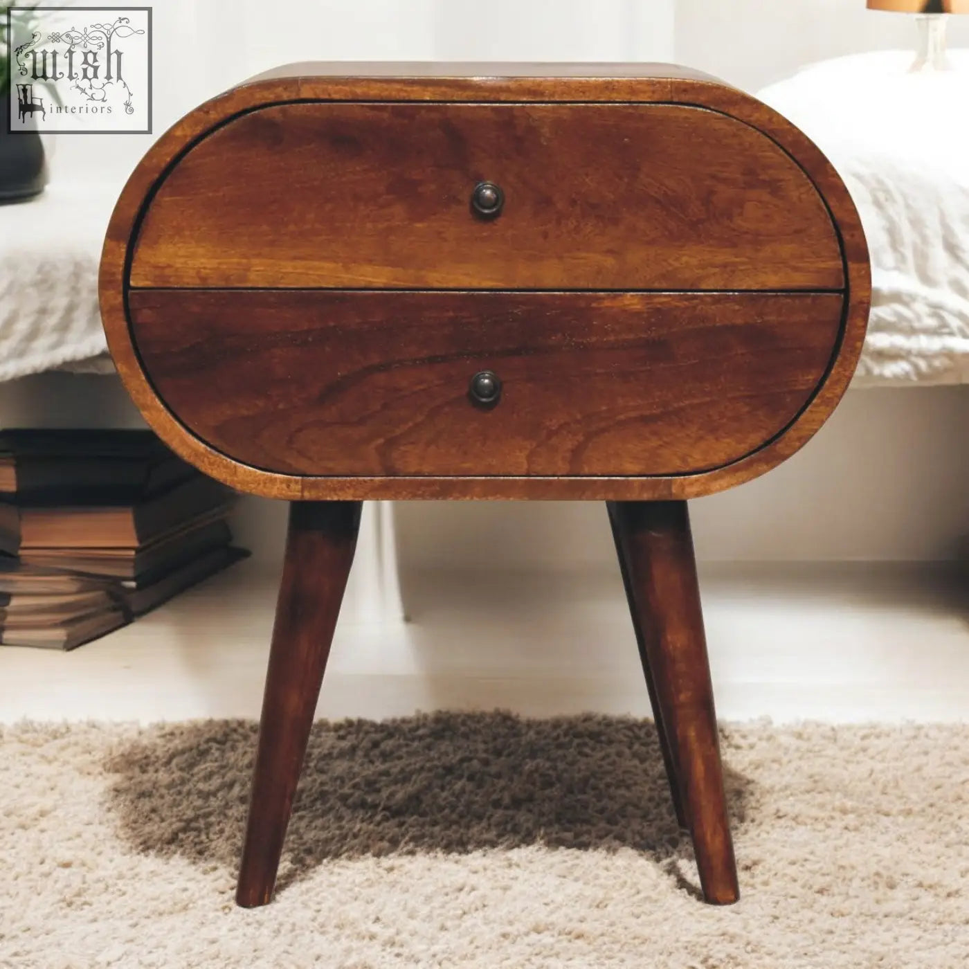 A large chestnut circular wooden bedside table with two drawers and tapered legs perfect for bedroom storage