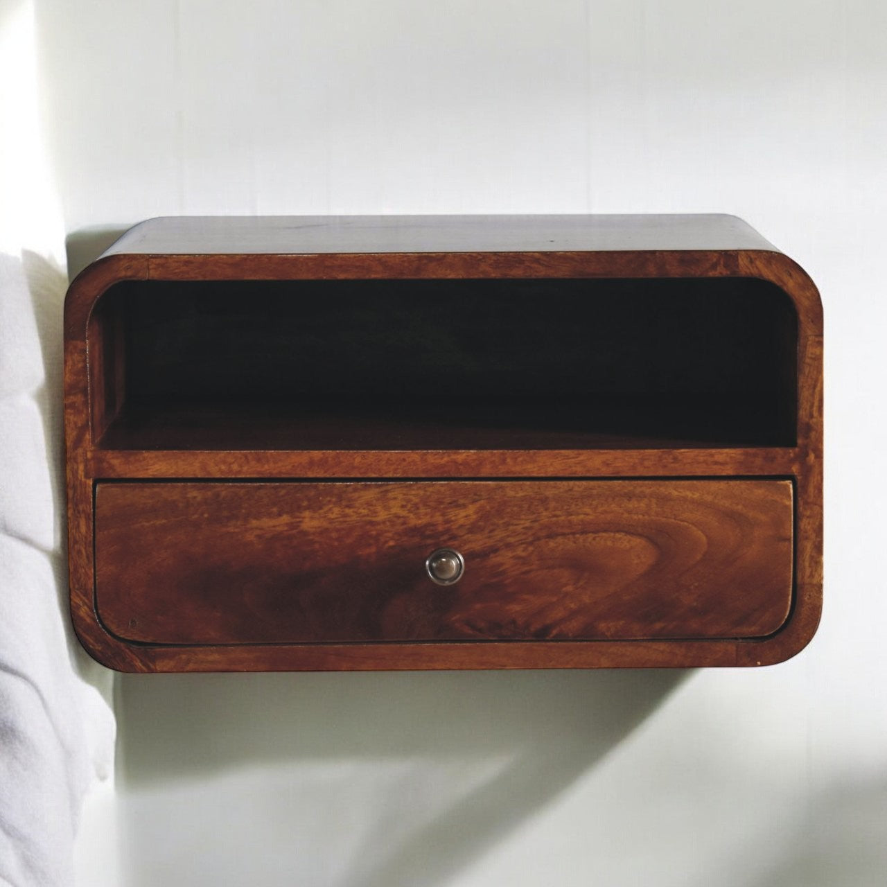 A sleek dark brown wooden floating bedside table with a large chestnut curve and upper slot drawer