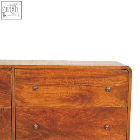 Large curved chestnut finish wooden dresser with rounded form factor and matching metallic knobs in warm tones