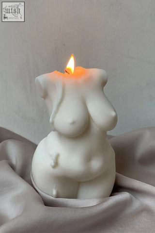 Large curvy body candle sculpted in white with a smooth minimalist design and a lit flame shaped like a female figure