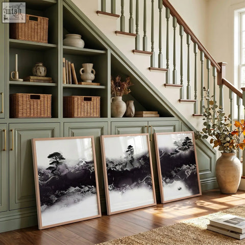Three large japanese wall art prints in black and white ink with minimalist wooden frames lean against a green cabinet