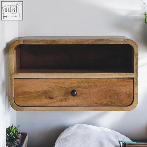 A sleek light wood floating bedside table with upper slot drawer and open shelf made of mango wood