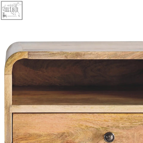 A rustic large oak-ish curve upper slot floating bedside table in light mango wood with natural grain patterns