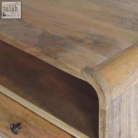 A rustic large oak-ish curve upper slot floating bedside table in warm mango wood with natural grain patterns