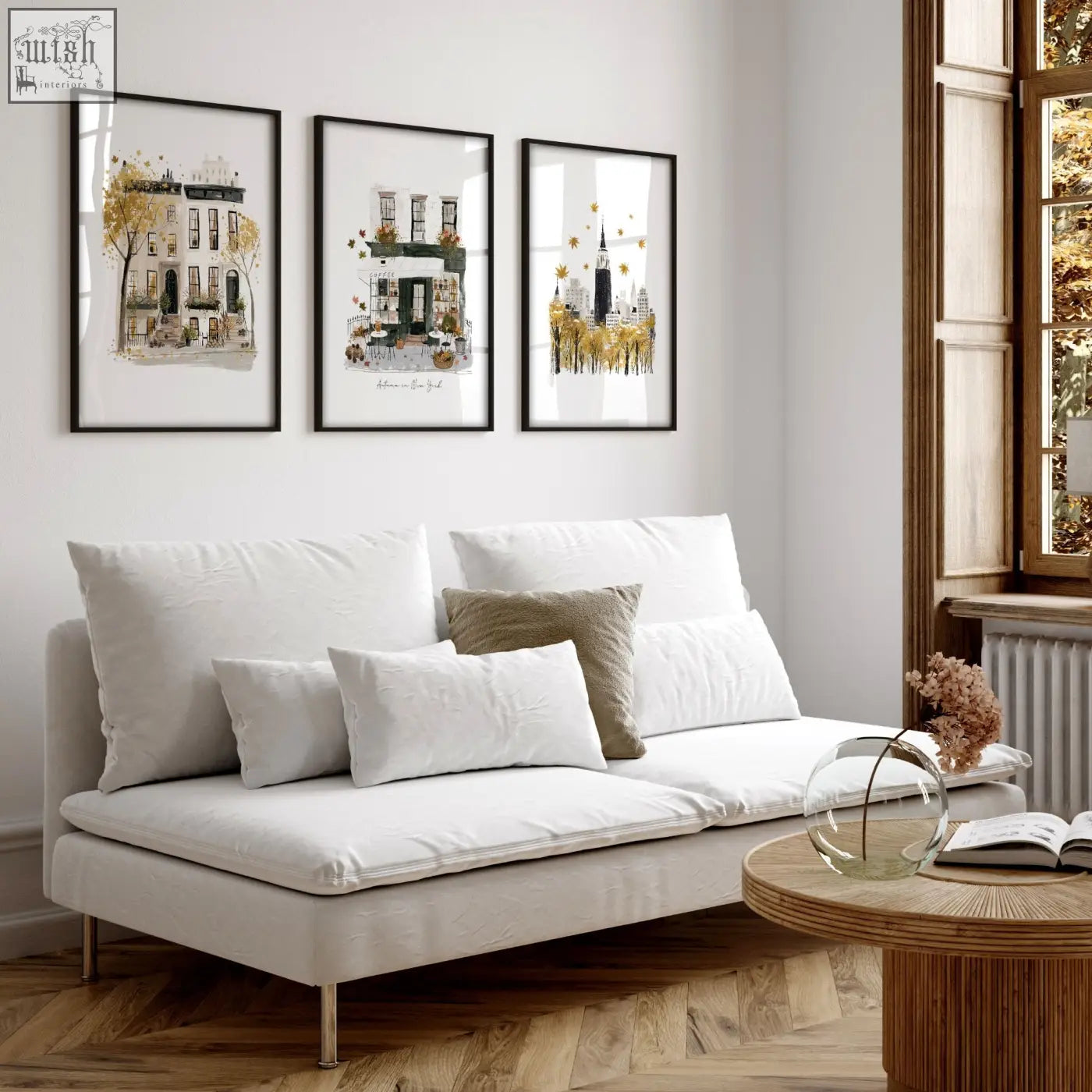 White upholstered sofa with metallic legs and cushions below large autumn in new york living room wall art prints set of 3
