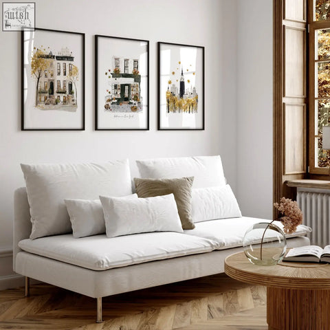 White upholstered sofa with metallic legs and cushions below large autumn in new york living room wall art prints set of 3