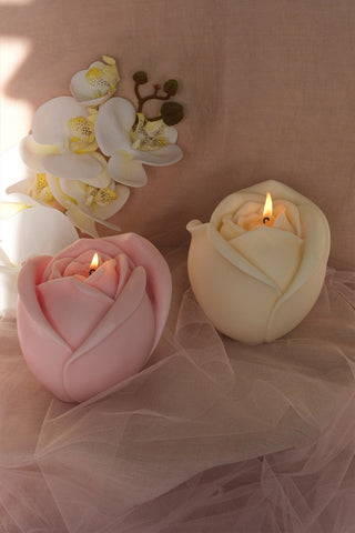 Large valentine’s day rose shaped candle in pink and cream made of smooth wax with lit wicks perfect for valentine’s day